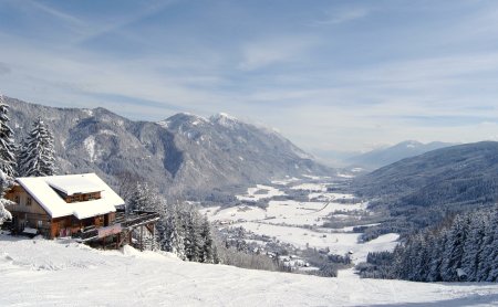 Holzhütte im Schnee mit Blick ins verschneite Tal