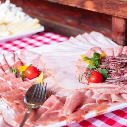 Platte mit Wurst und Schinken auf rot-weißem Tischtuch
