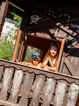 Lachende Kinder im offenen Fenster des Spielhauses