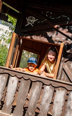 Lachende Kinder im offenen Fenster des Spielhauses