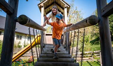 Two kids crossing the wooden rope bridge together