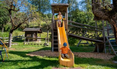 Boy slides down, girl stands atop the slide