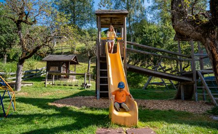 Junge rutscht, Mädchen steht oben auf der Rutsche