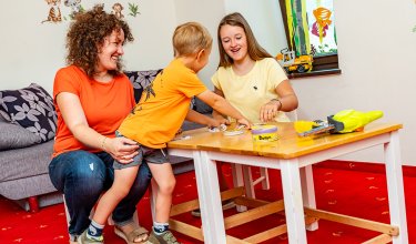 Boy reaching for card while playing with family
