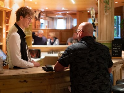 Gast im Gespräch mit Kellner an der Hotelbar