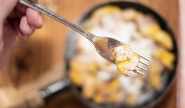 Gabel mit Kaiserschmarrn über gusseiserner Pfanne