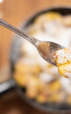 Gabel mit Kaiserschmarrn über gusseiserner Pfanne