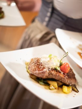 Drei angerichtete Steaks auf weißen Tellern im Service