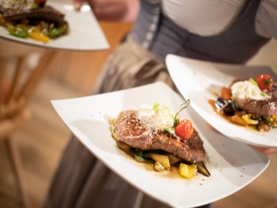 Drei angerichtete Steaks auf weißen Tellern im Service