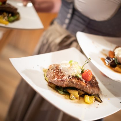 Drei angerichtete Steaks auf weißen Tellern im Service