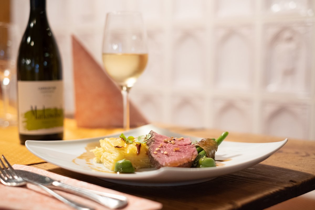 Feines Hauptgericht mit Weißwein auf Holztisch