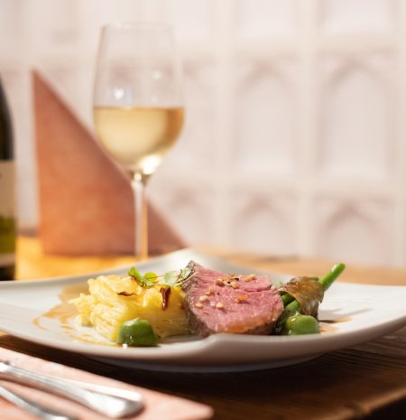Feines Hauptgericht mit Weißwein auf Holztisch