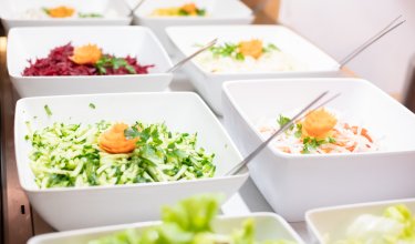 Salatbuffet mit geraspeltem Gemüse in weißen Schüsseln