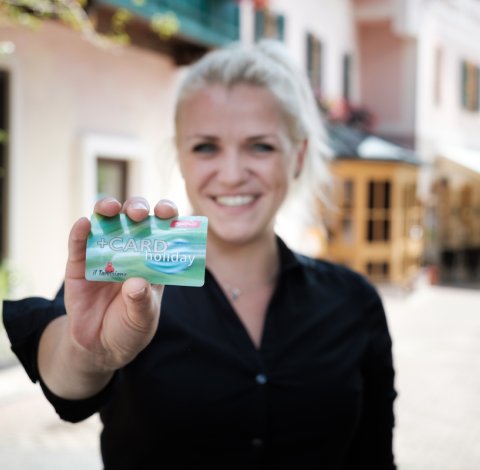 Lächelnde Mitarbeiterin zeigt die Nassfeld +CARD draußen