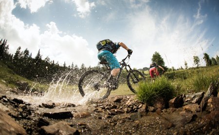 Actionreiche Mountainbike Fahrt durch spritzenden Bach