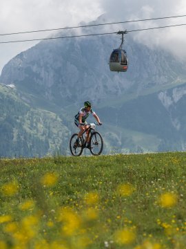 Biker unter Gondelbahn mit Bergpanorama