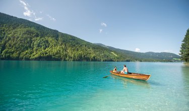 Vater und Kind rudern auf türkisblauem See