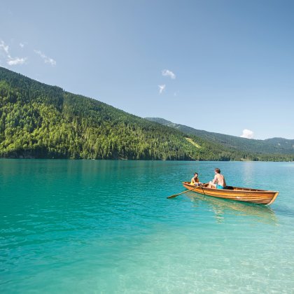 Vater und Kind rudern auf türkisblauem See