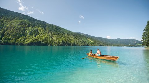 Vater und Kind rudern auf türkisblauem See