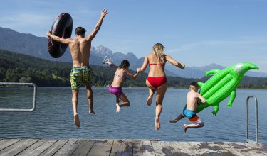 Familie springt gemeinsam vom Badesteg
