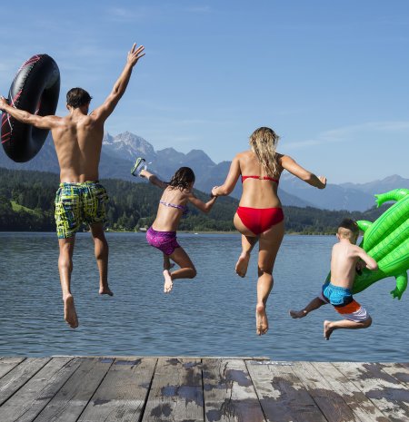 Familie springt gemeinsam vom Badesteg