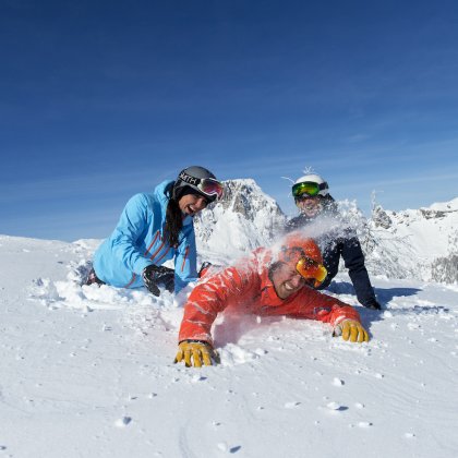 Freunde spielen lachend im Tiefschnee