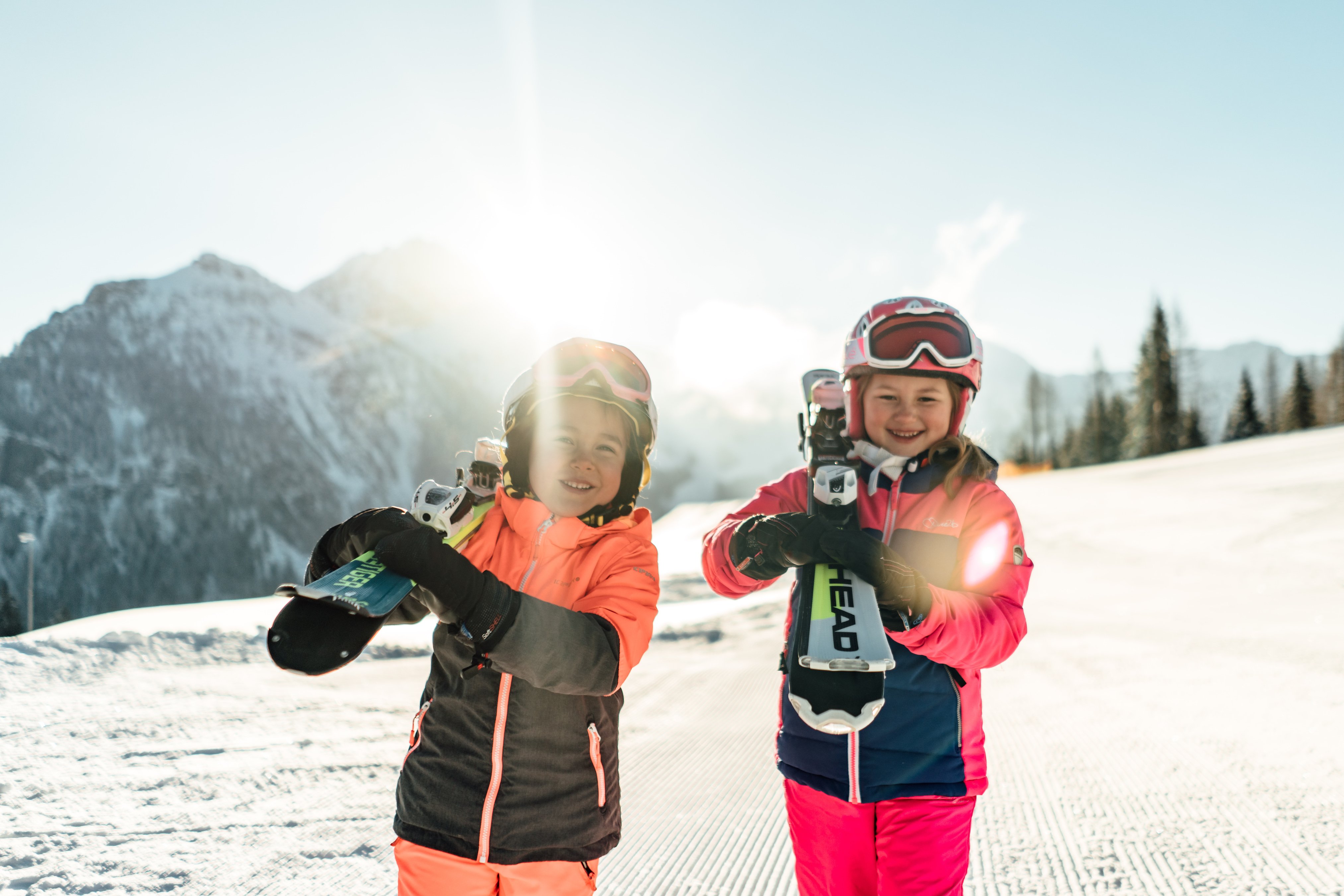 Zwei Kinder halten stolz ihre Skier in der Hand