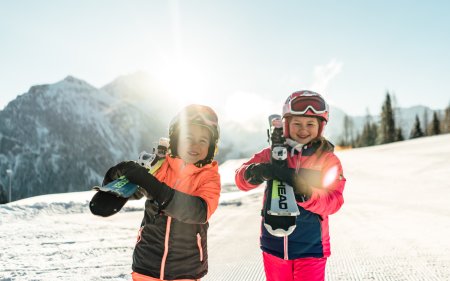 Two kids proudly holding their skis