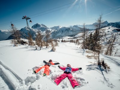 Zwei Kinder machen Schneeengel im Pulverschnee