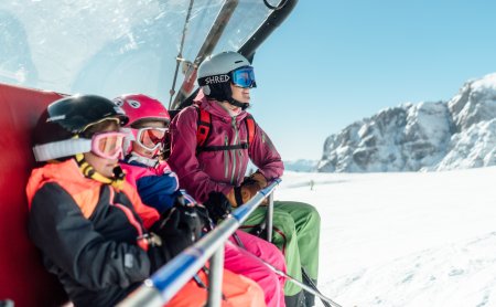 Familie fährt im Sessellift durch Winterlandschaft