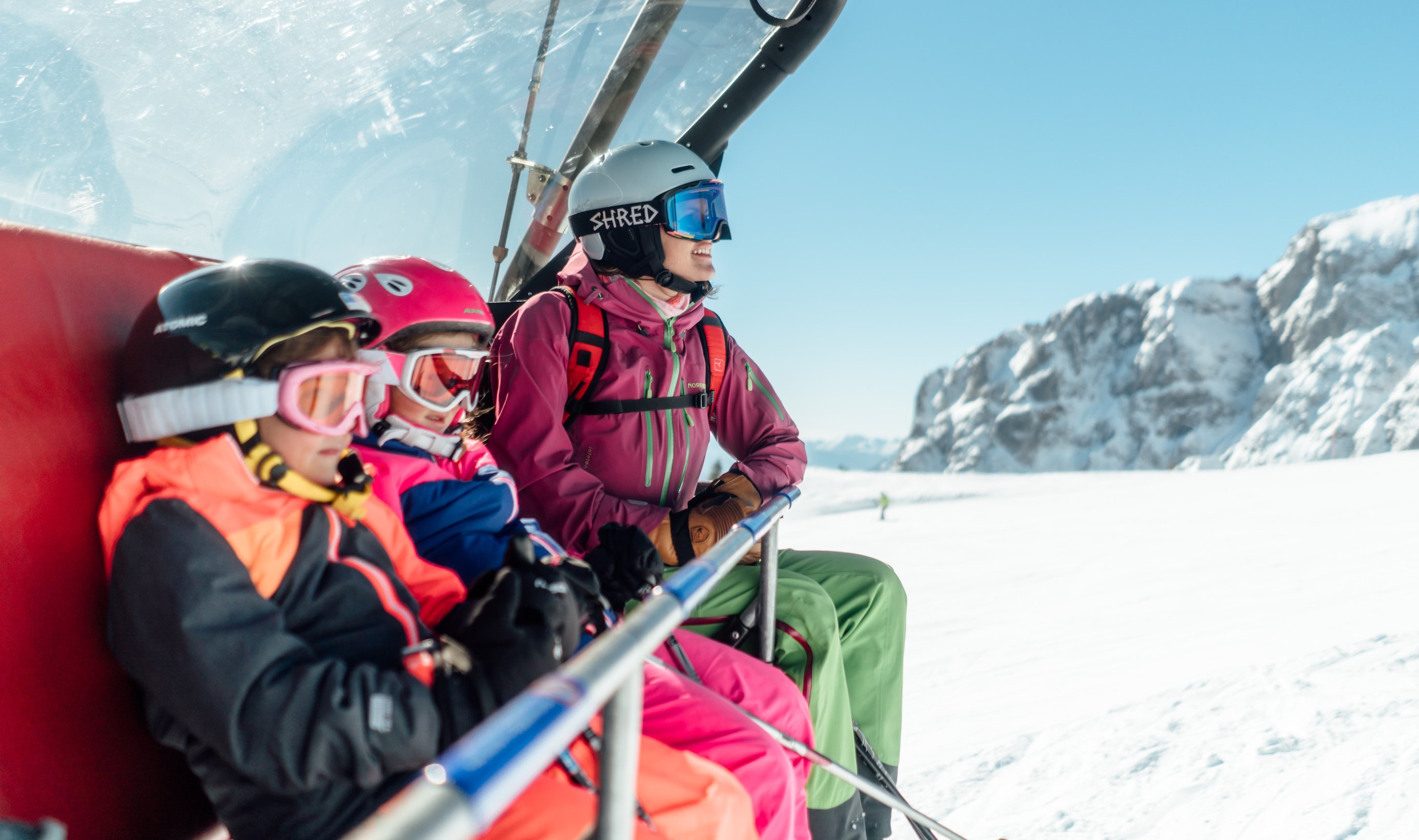 Familie fährt im Sessellift durch Winterlandschaft