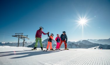 Familie auf der Skipiste bei strahlendem Sonnenschein, die sich gegenseitig abklatschen