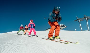 Skilehrer führt Kindergruppe auf der Piste