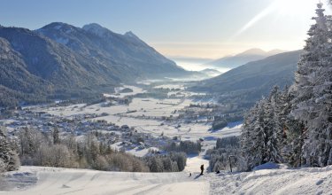Blick von der Piste auf verschneites Tal