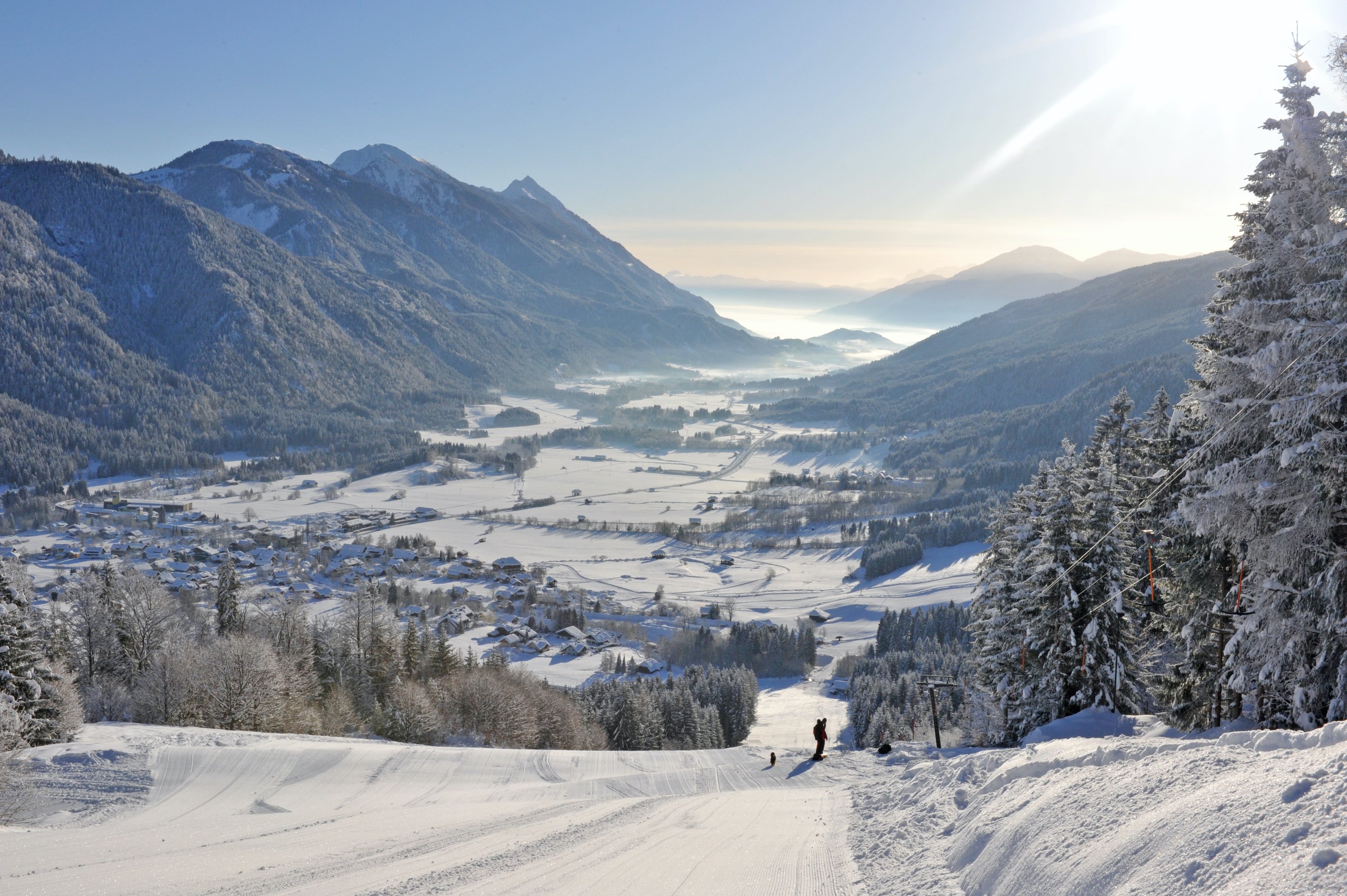 Blick von der Piste auf verschneites Tal