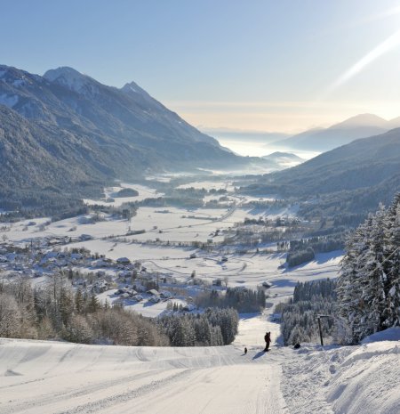 Blick von der Piste auf verschneites Tal