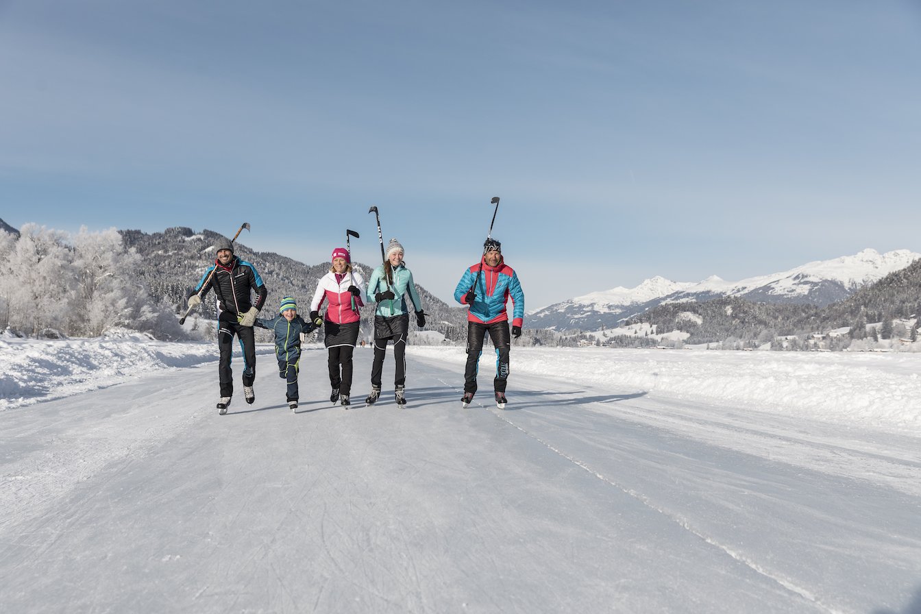 Familie mit Eislaufschuhen und Stöcken auf dem Eis