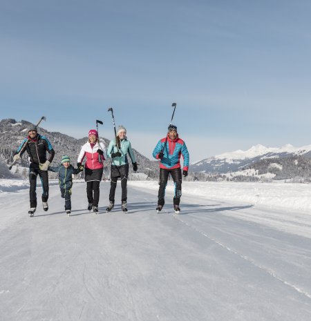 Familie mit Eislaufschuhen und Stöcken auf dem Eis