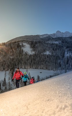 Winterwanderung mit Familie bei Sonnenuntergang