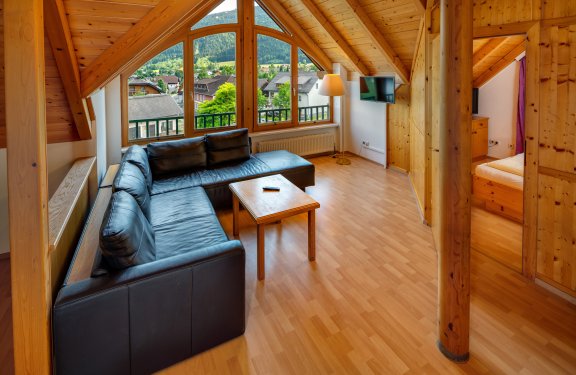 Wohnbereich mit schwarzem Sofa und großem Fensterblick