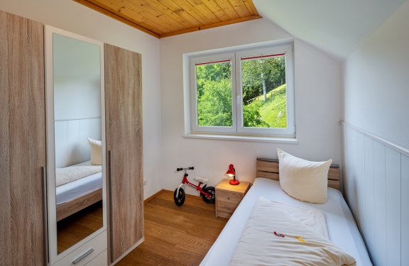 Kinderzimmer mit Einzelbett, Laufrad und Blick ins Grüne