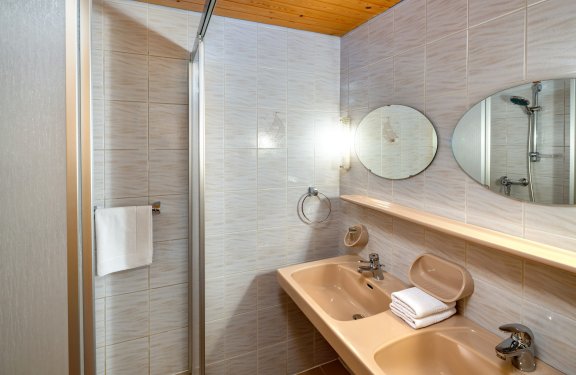 Badezimmer mit zwei Waschbecken und Duschkabine