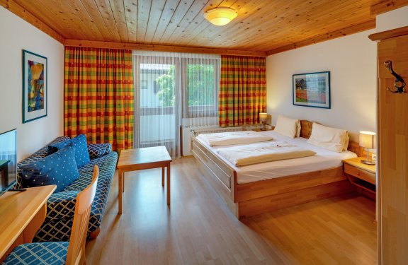 Gemütliches Zimmer mit Holzdecke und Balkonzugang