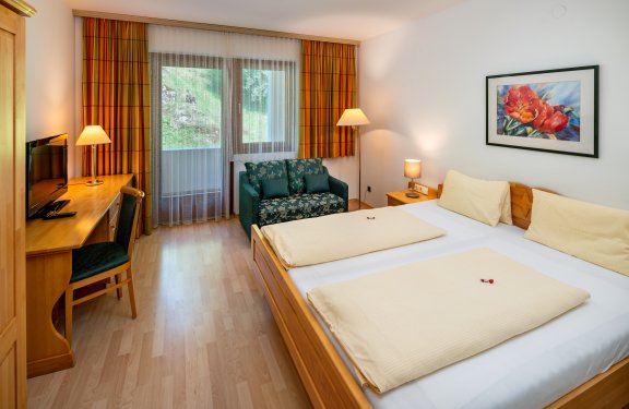 Helles Zimmer mit Doppelbett, Sofa und Schreibtisch