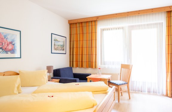 Gemütliches Doppelzimmer mit Sofa und hellem Vorhang