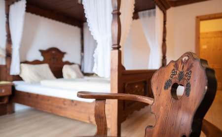 Gemütliches Zimmer mit Himmelbett und Stuhl mit Herzlehne