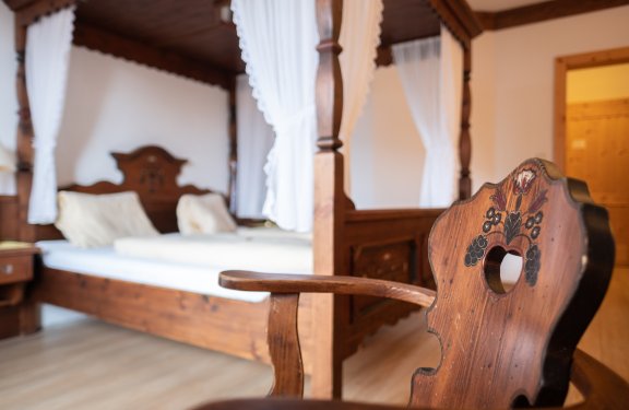 Gemütliches Zimmer mit Himmelbett und Stuhl mit Herzlehne