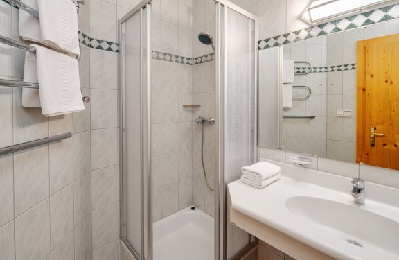 Badezimmer mit Dusche und weißen Fliesen