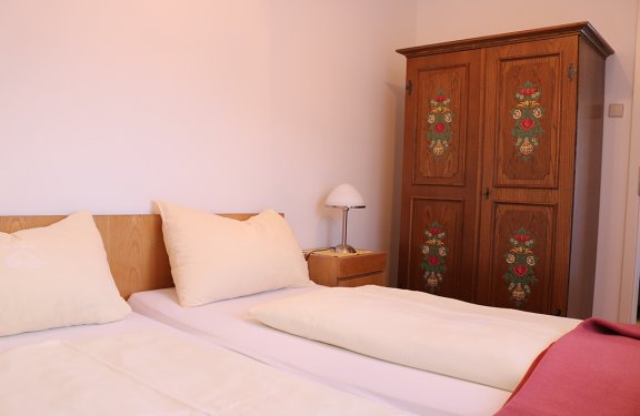 Bright bedroom with two beds, bedside lamp, and painted wooden wardrobe